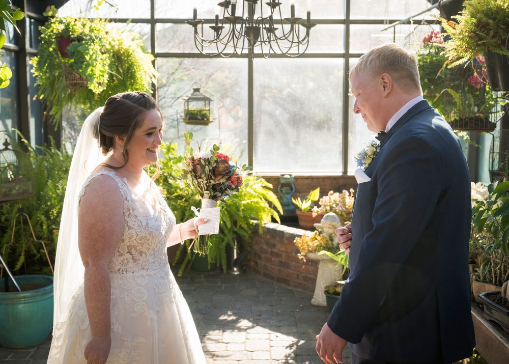 Wedding ceremony in a bright greenhouse with natural light streaming through glass windows.