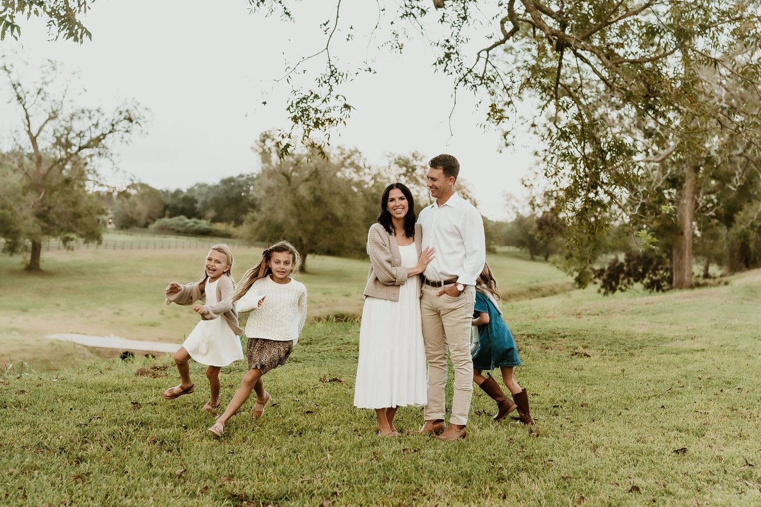 Family plays together on grassy hillside during outdoor photo session.