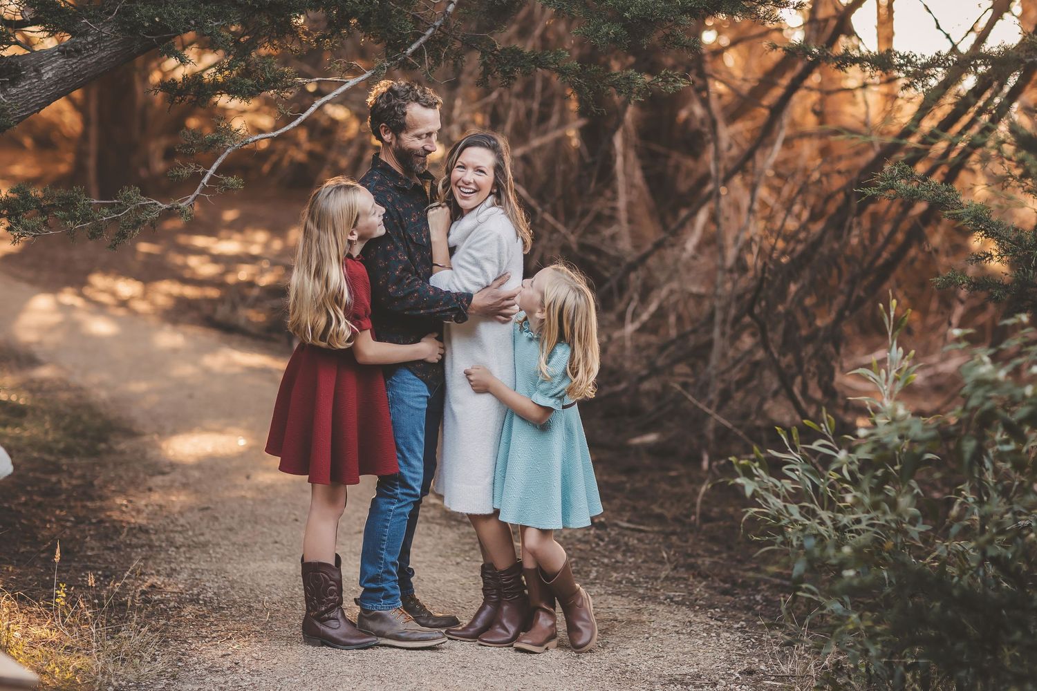 Family sharing tender moments together in a sunlit meadow with delicate white wildflowers and autumn foliage.