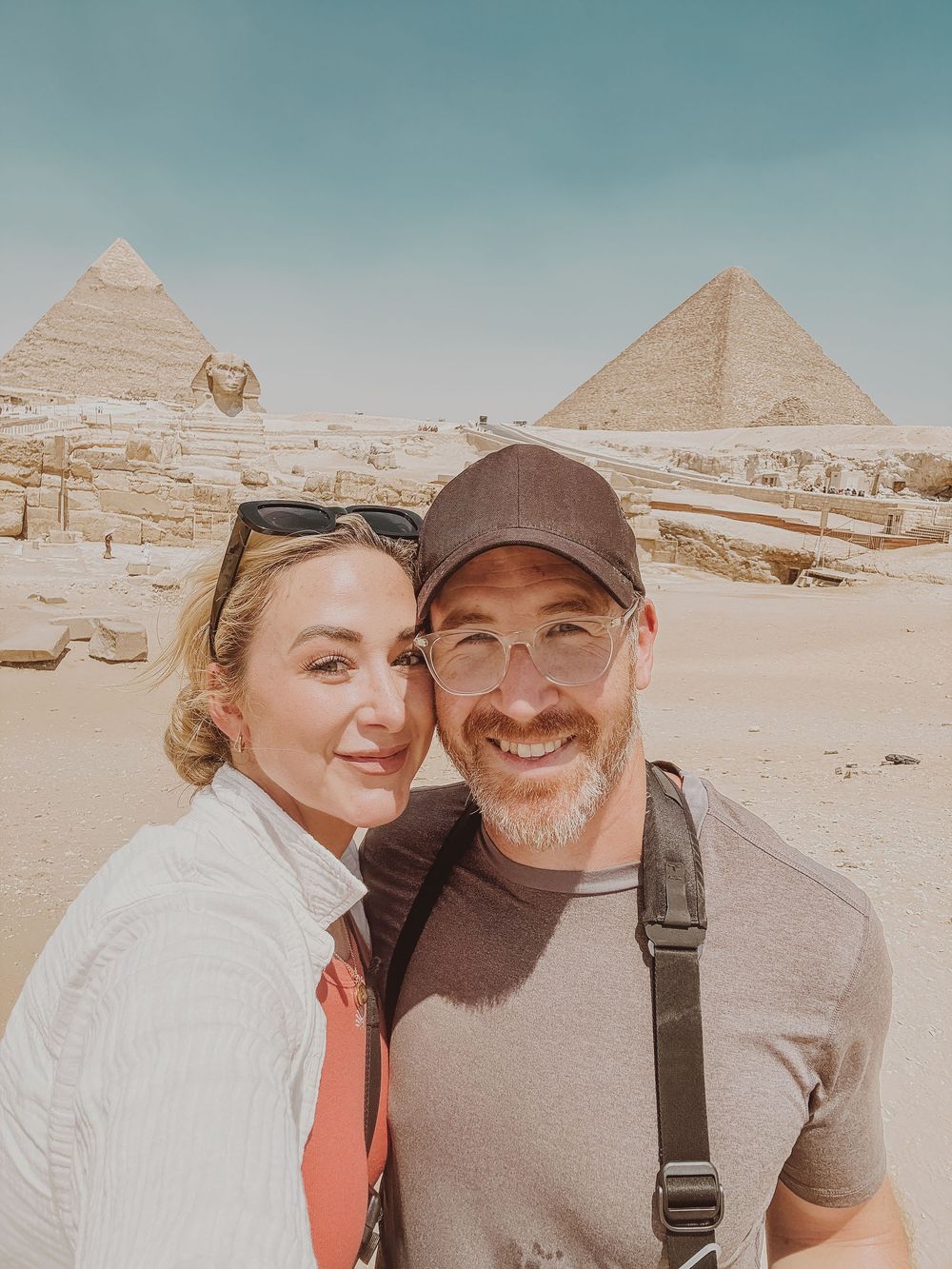 Tourists take selfie photos together with the iconic pyramids and Sphinx of Giza in Egypt visible in the background.