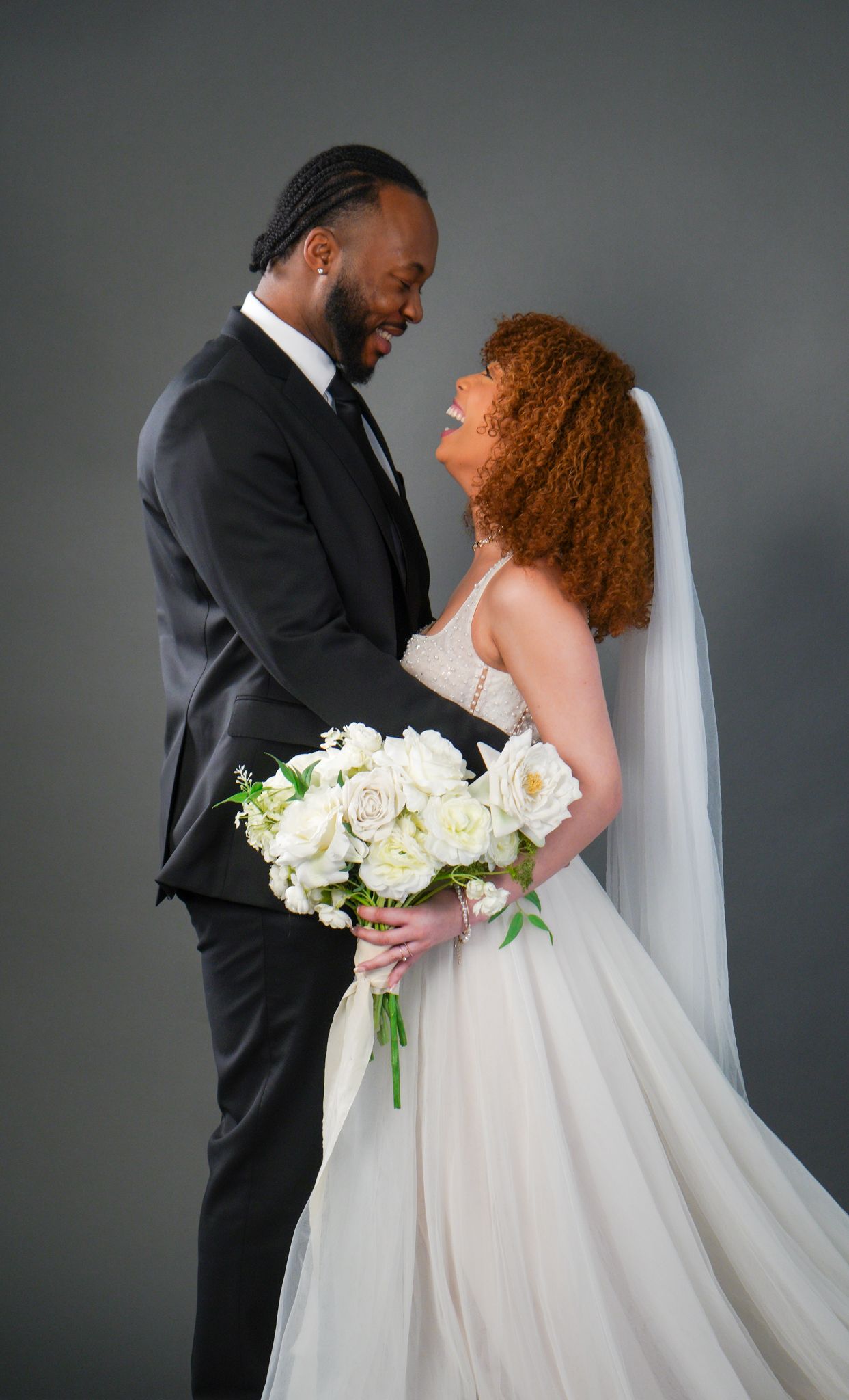 A romantic wedding portrait of a couple sharing an intimate moment with a white bouquet.