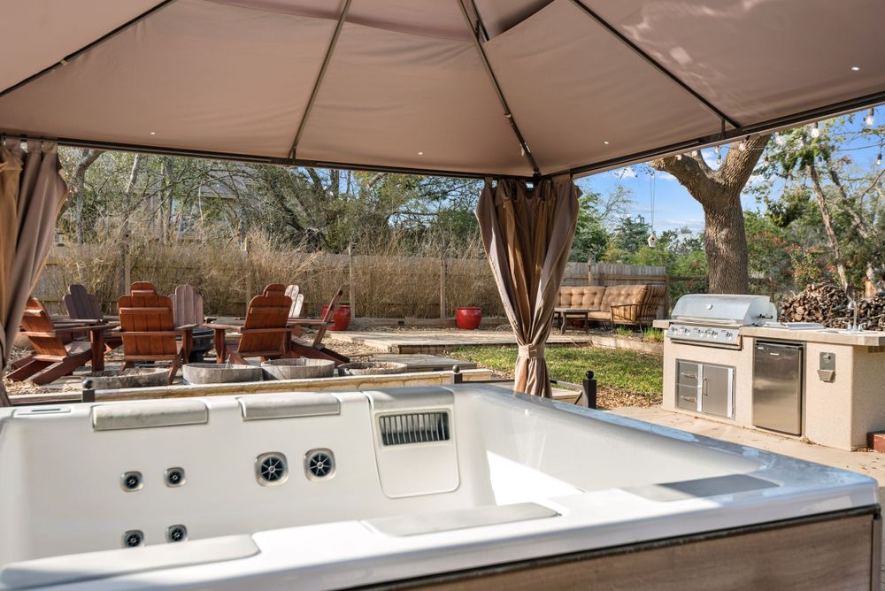 Covered outdoor spa area with gazebo and built-in grill station.