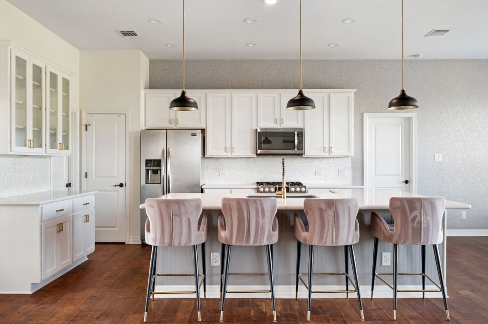 Modern white kitchen with plush velvet barstools and pendant lighting at an island counter.