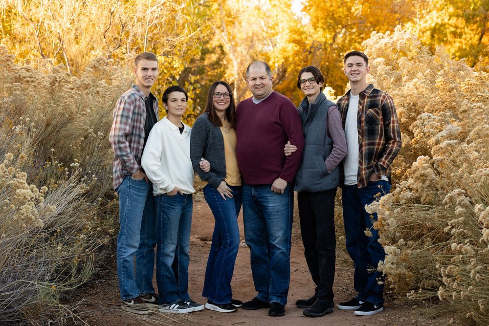family with 4 boys in fall outfits smiling at the camera with faded yellow desert blooms