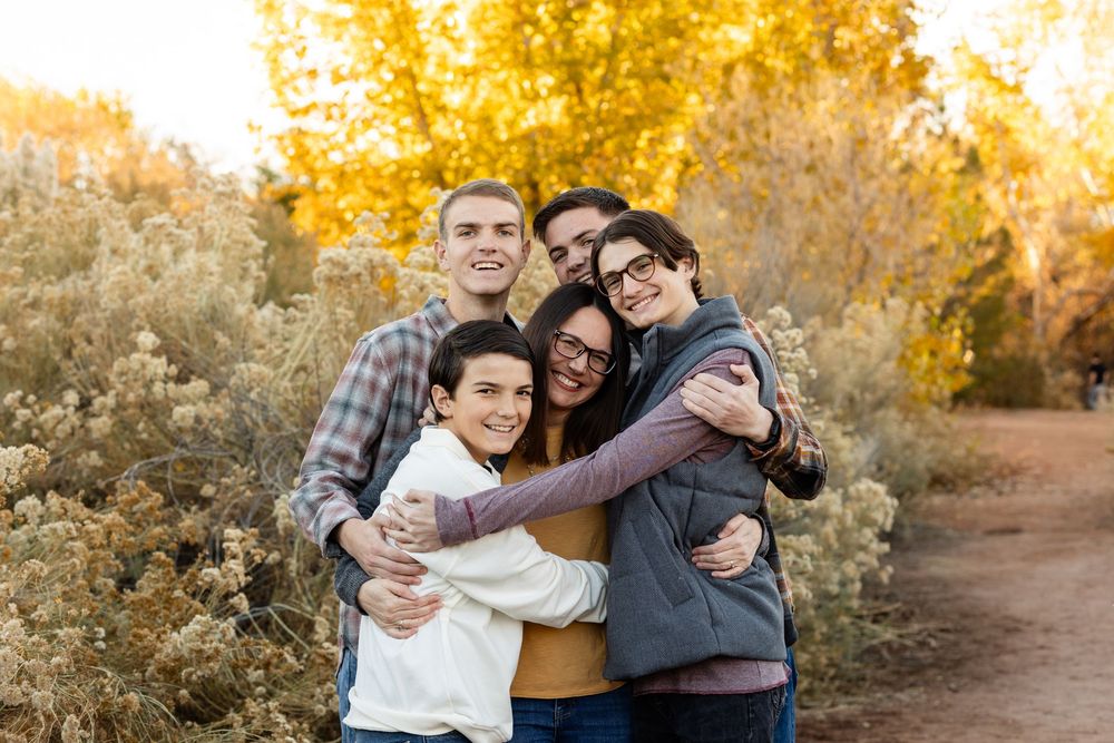 southern utah  family photos mom and 4 boys hugging and laughing at the camera with faded yellow blooms