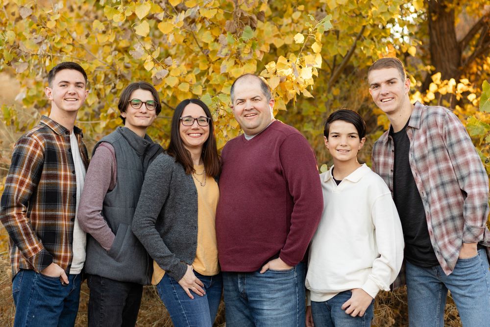 St. George Utah family of 6 smiling at the camera with fall leaves in the background