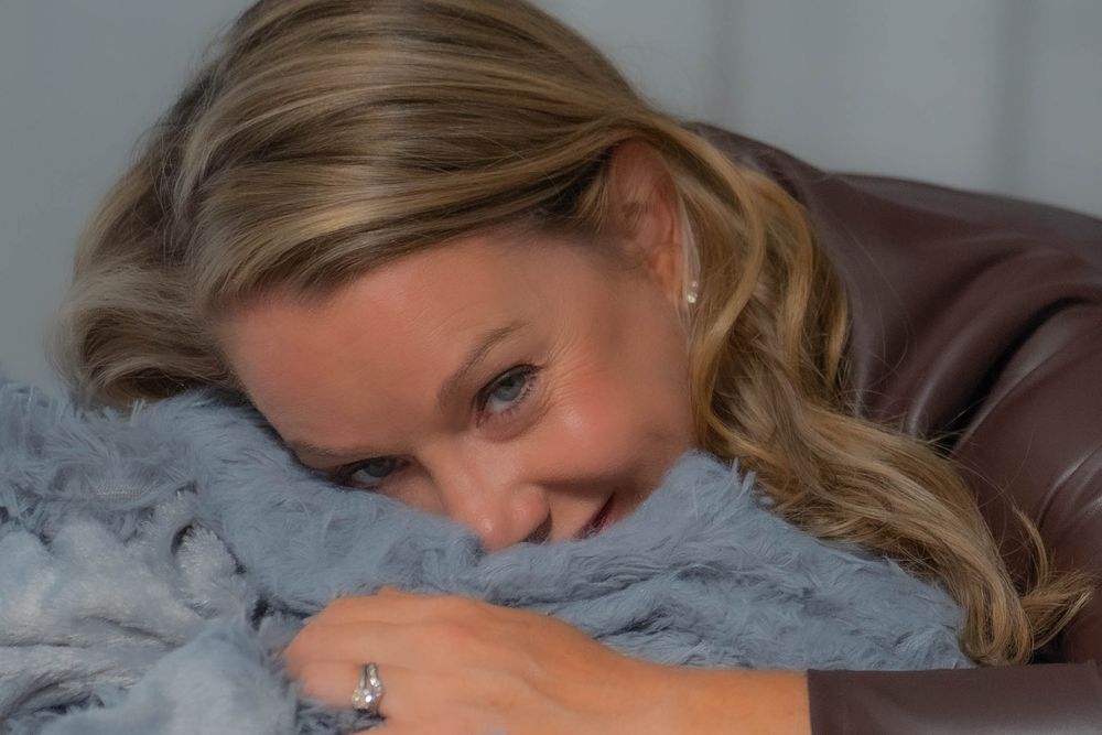 Person resting on grey textured surface in relaxed indoor pose.