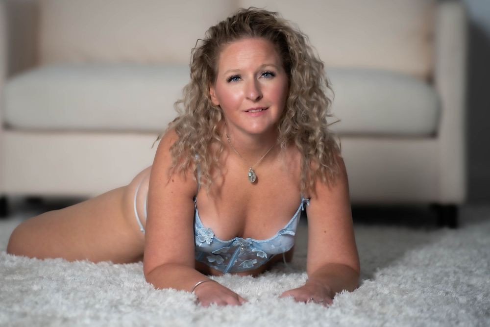 Artistic boudoir photography session on light carpet in casual attire.