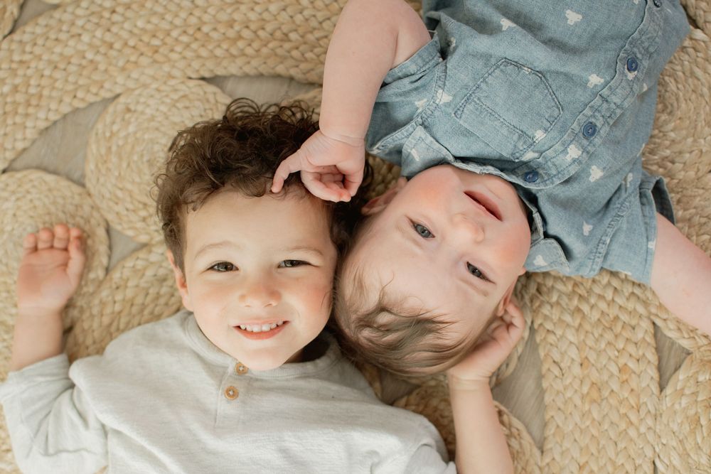 Mother and child cuddling together on a cozy beige rug in heartwarming candid moment.