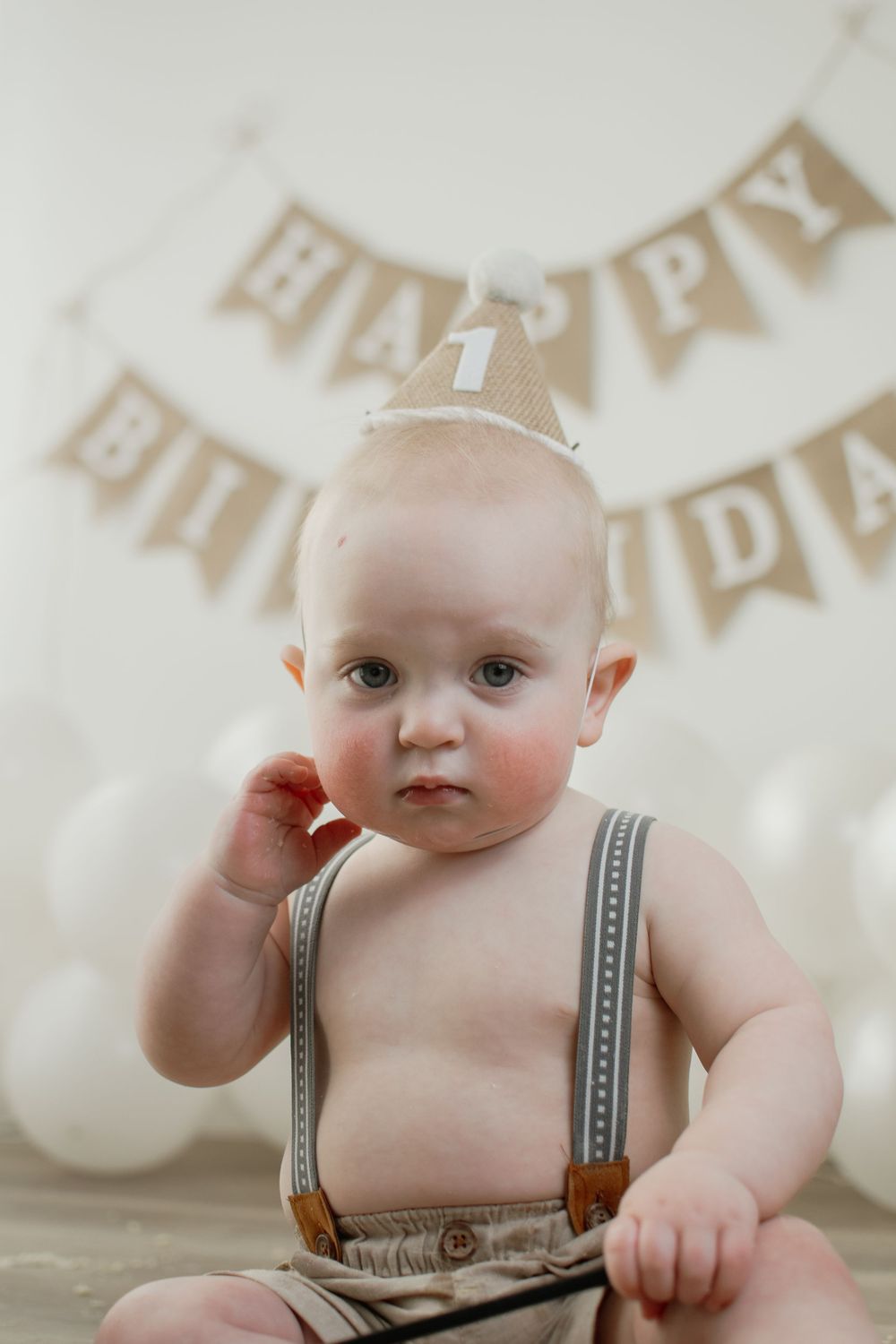 A series of five portrait photos showing a baby in striped overalls against a light background with banner decorations.