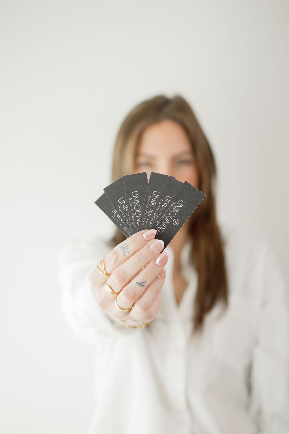 Three minimalist photos show hands holding black playing cards with white text against a light background.