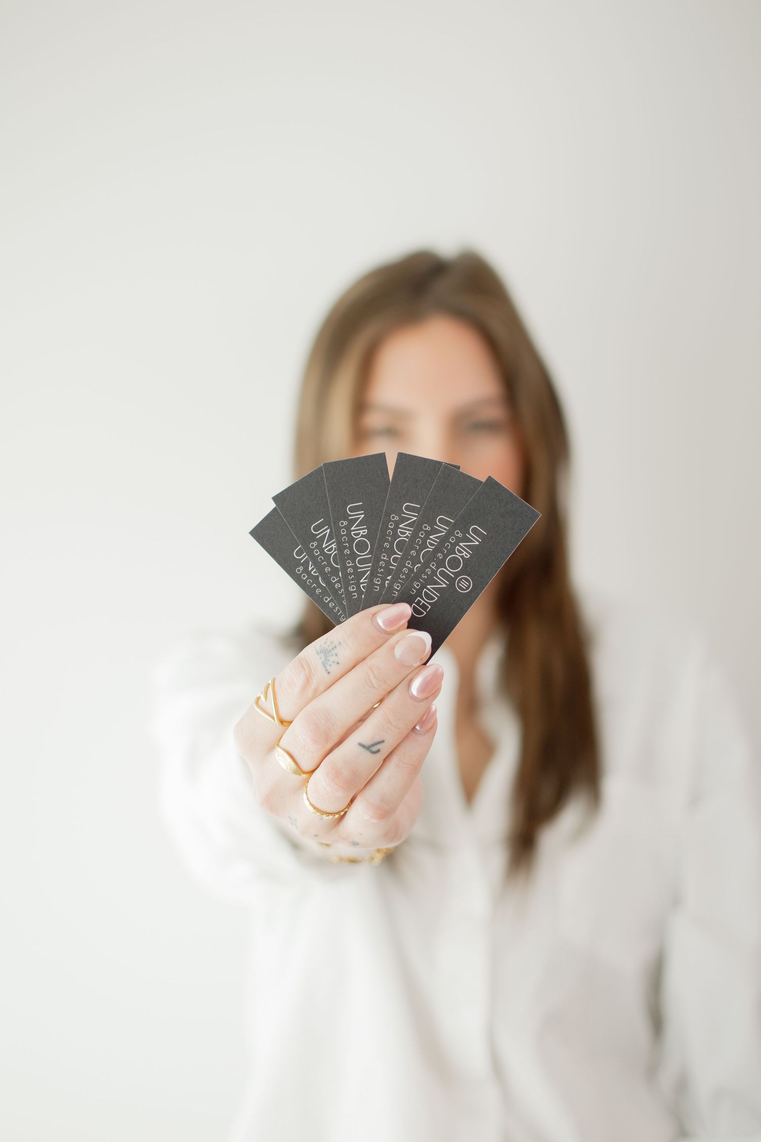 Three minimalist photos show hands holding black playing cards with white text against a light background.