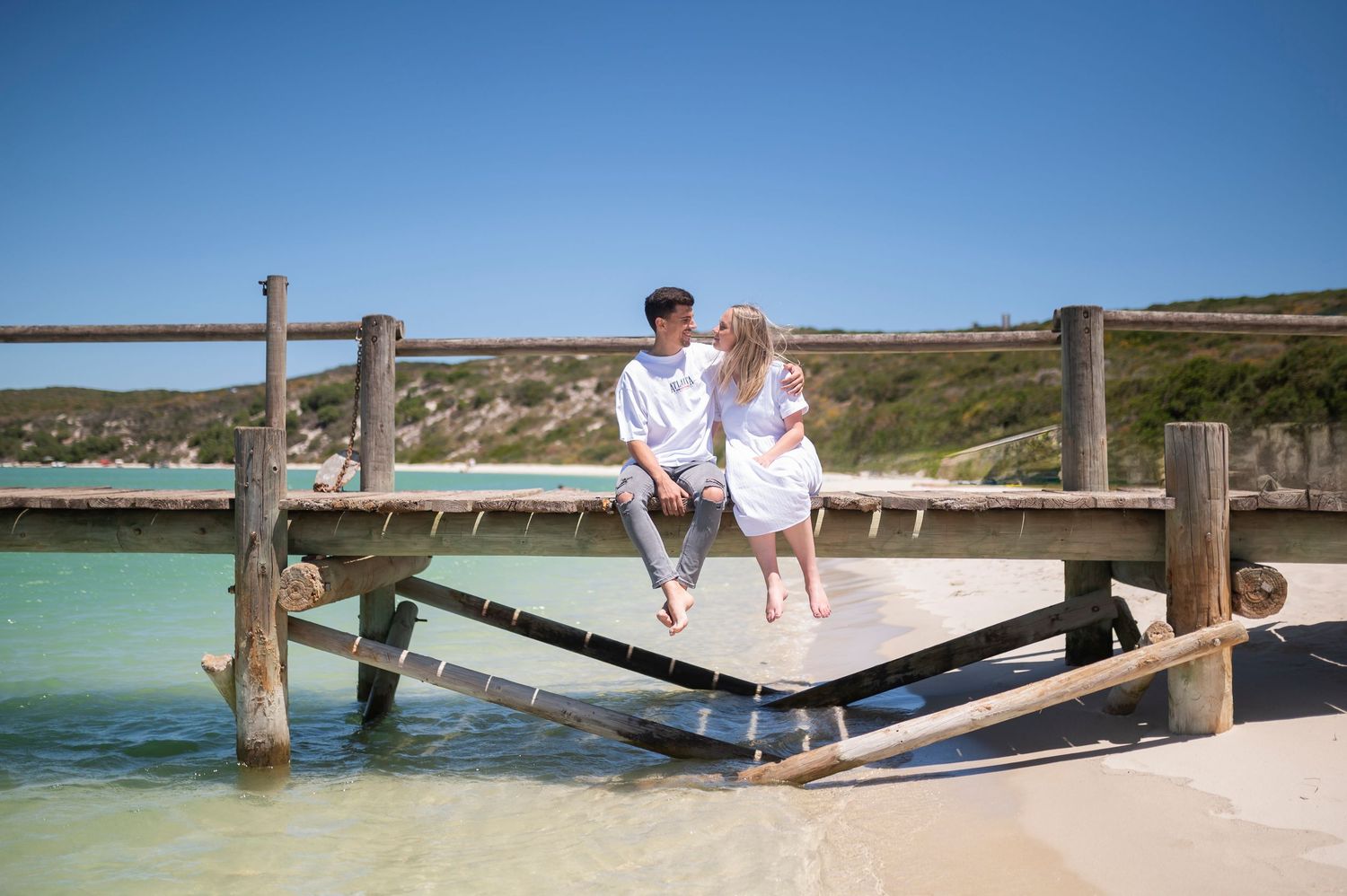 People enjoying a relaxing day at a scenic beach boardwalk with turquoise waters and coastal views.
