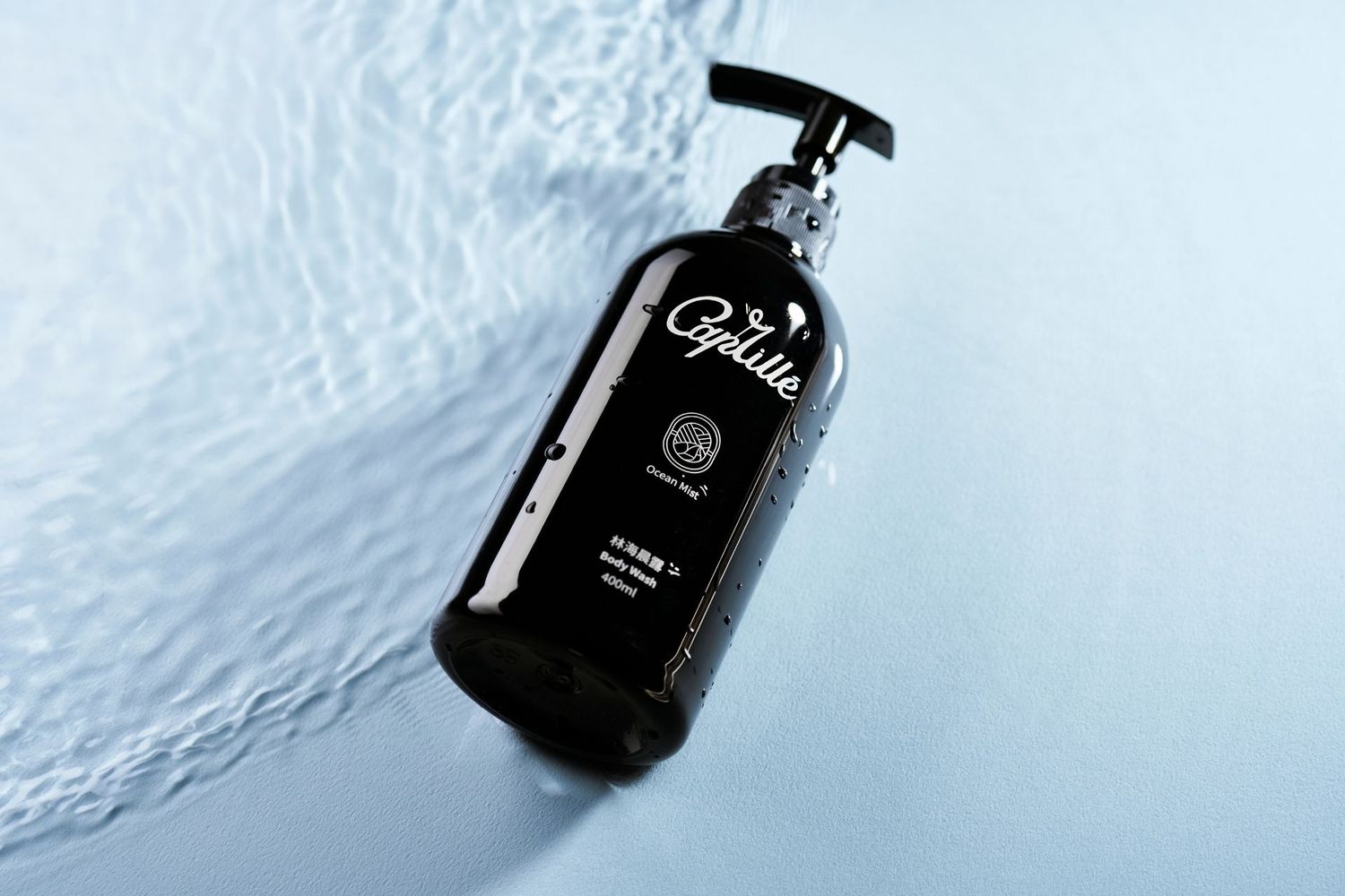 A set of dark glass bottles arranged in a row with white reflections on an icy or textured white surface.