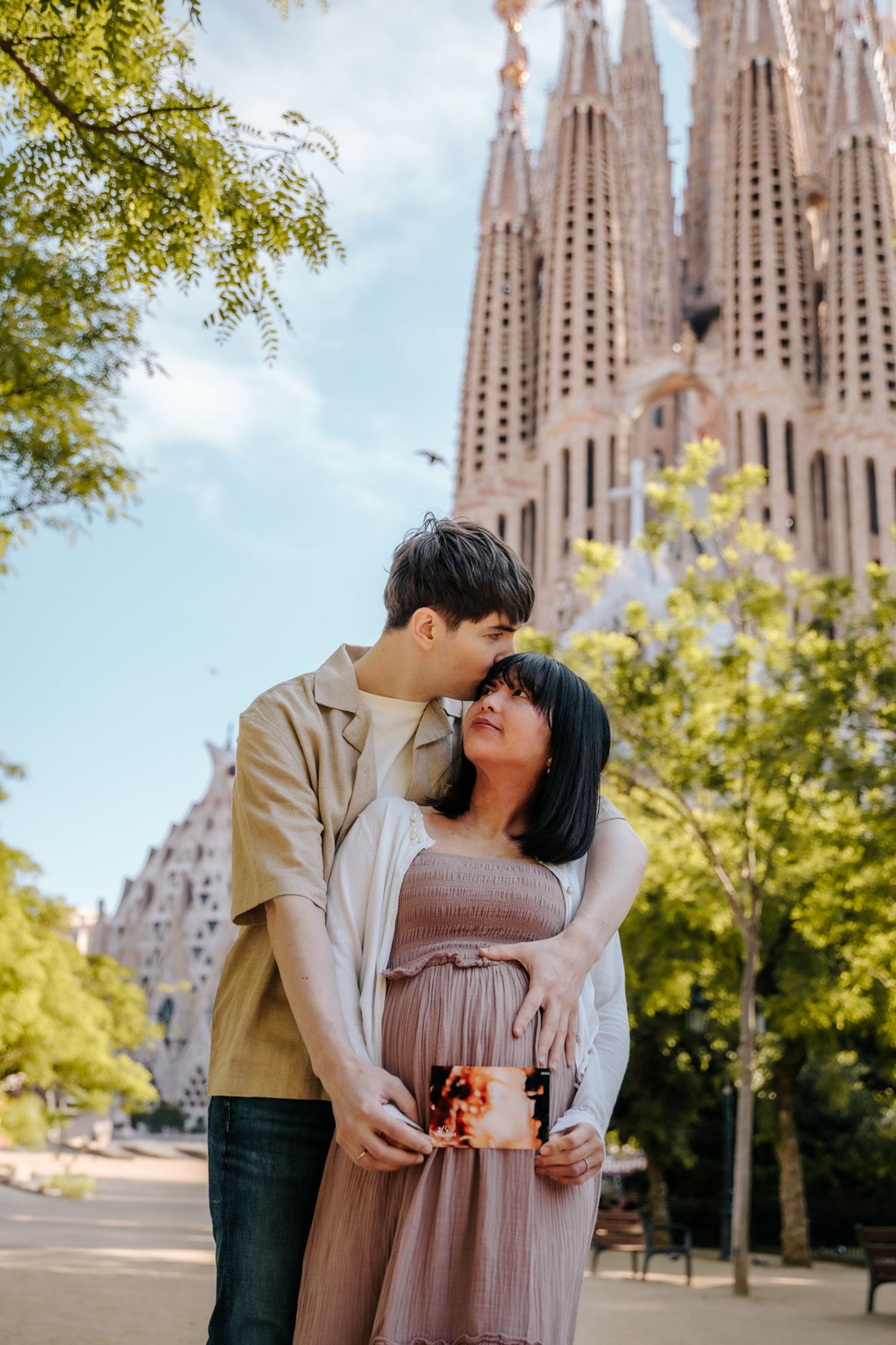 Expecting parents sharing laughter while posing in front of Sagrada Familia’s entrance.