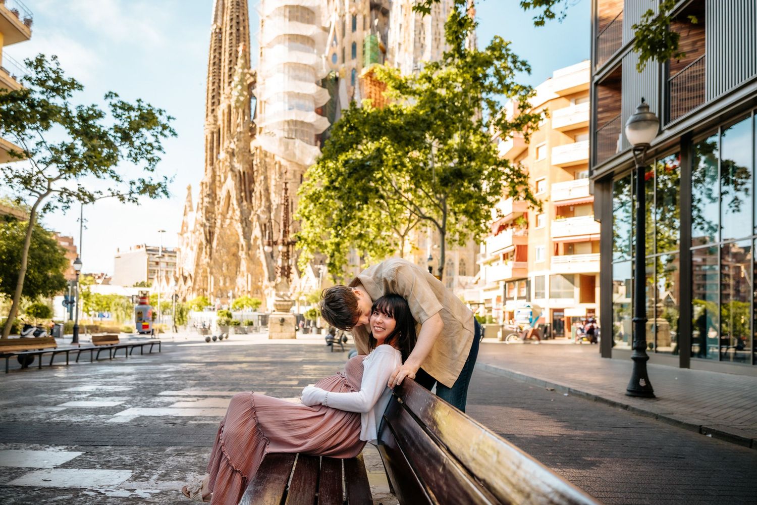 Hikari smiling tenderly as Ricard kisses her forehead at Sagrada Familia.