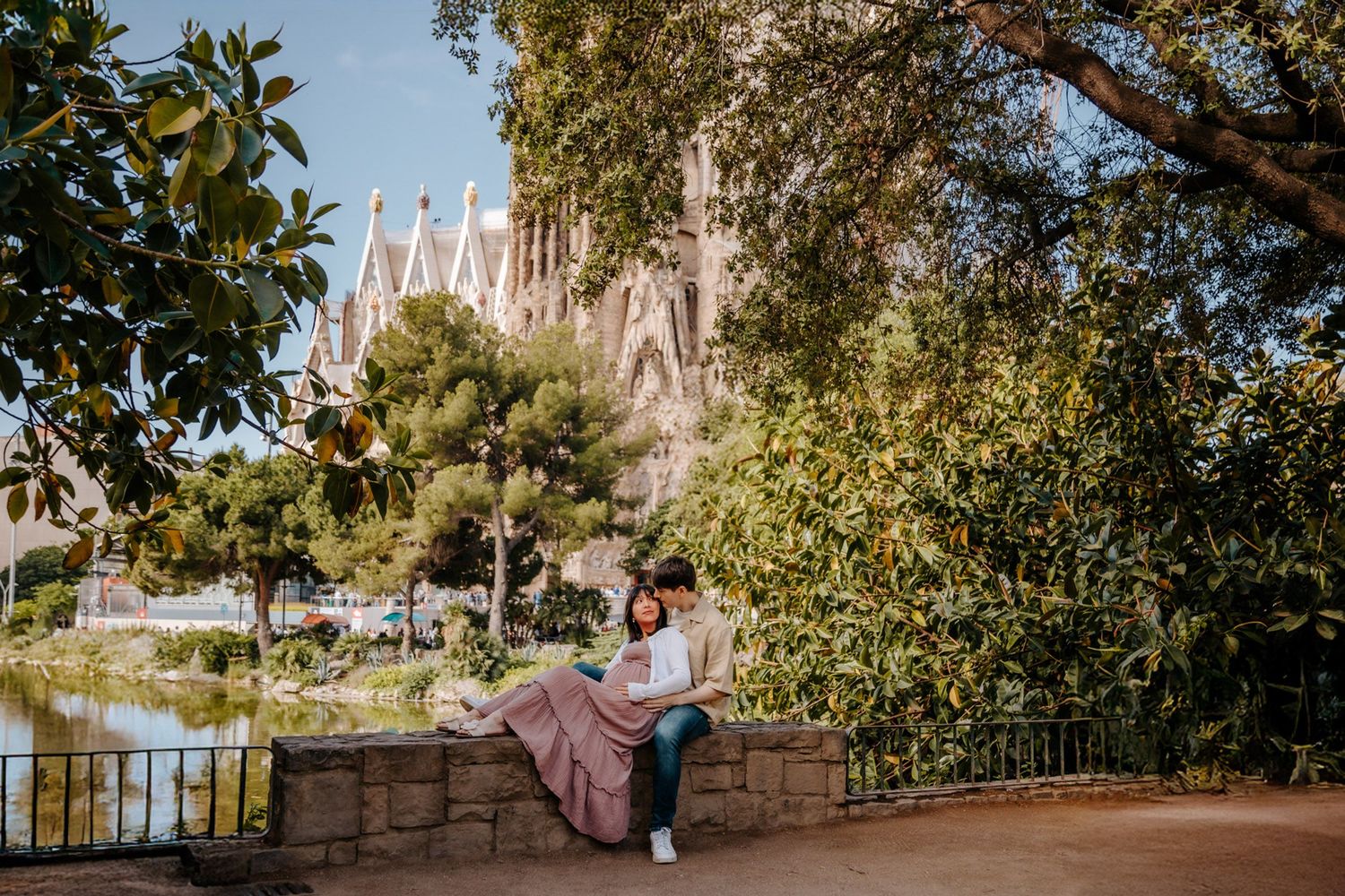 Expecting parents holding hands while admiring Sagrada Familia during their Barcelona maternity photoshoot.