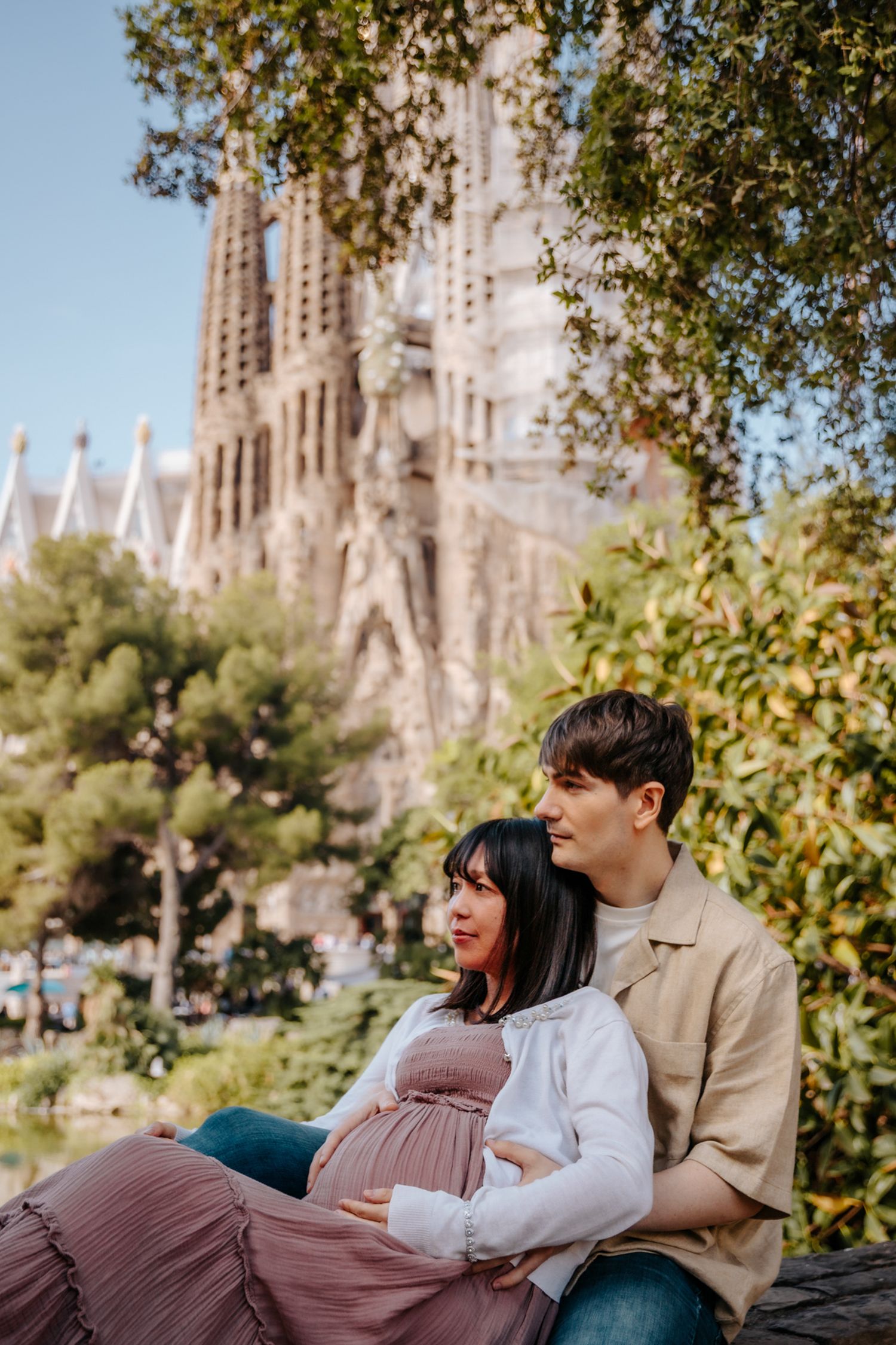 Expecting parents embracing softly with the majestic Sagrada Familia as their romantic maternity photoshoot backdrop.