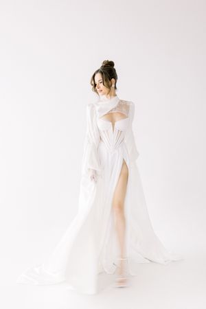 Ethereal white flowing dress with cutout details and high slit captured against minimal white background.