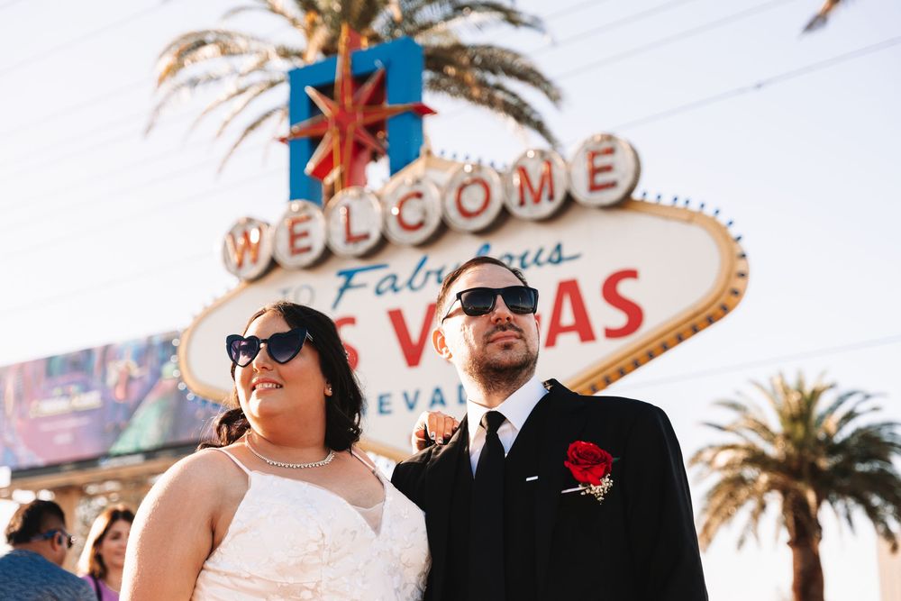 A couple shares a beautiful outdoor moment at dusk under palm trees and neon signs in Las Vegas, Nevada.