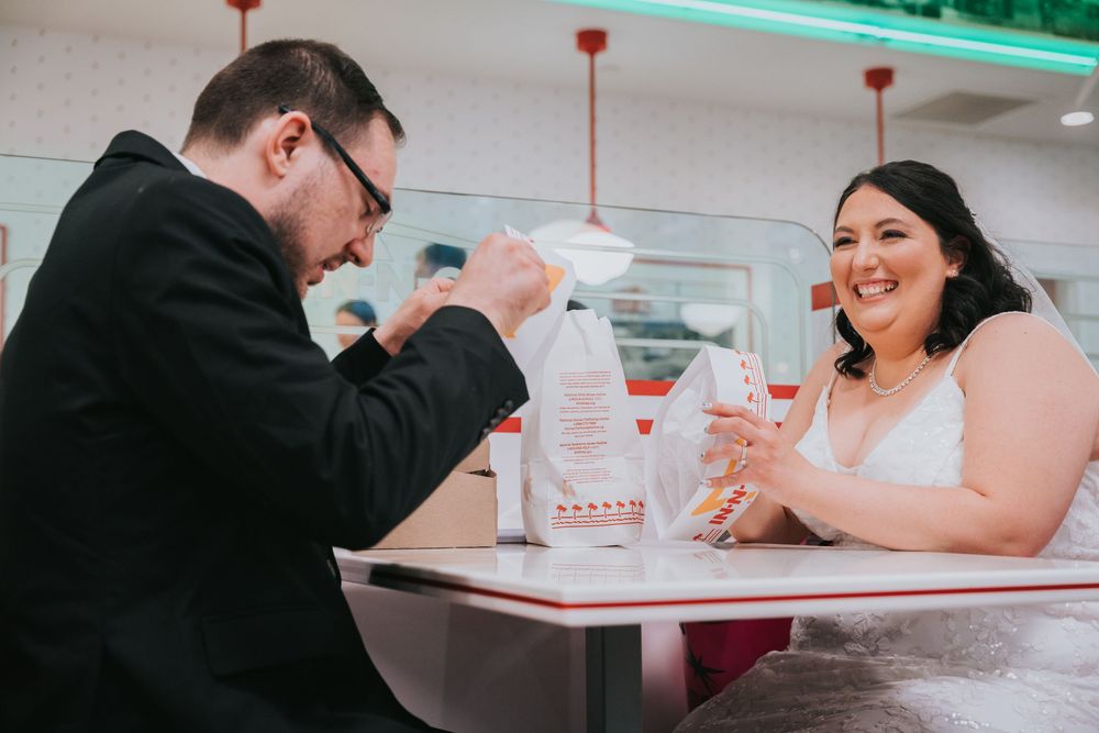 Two people enjoying milkshakes at a retro-style diner with neon lighting and red pendant lamps overhead.