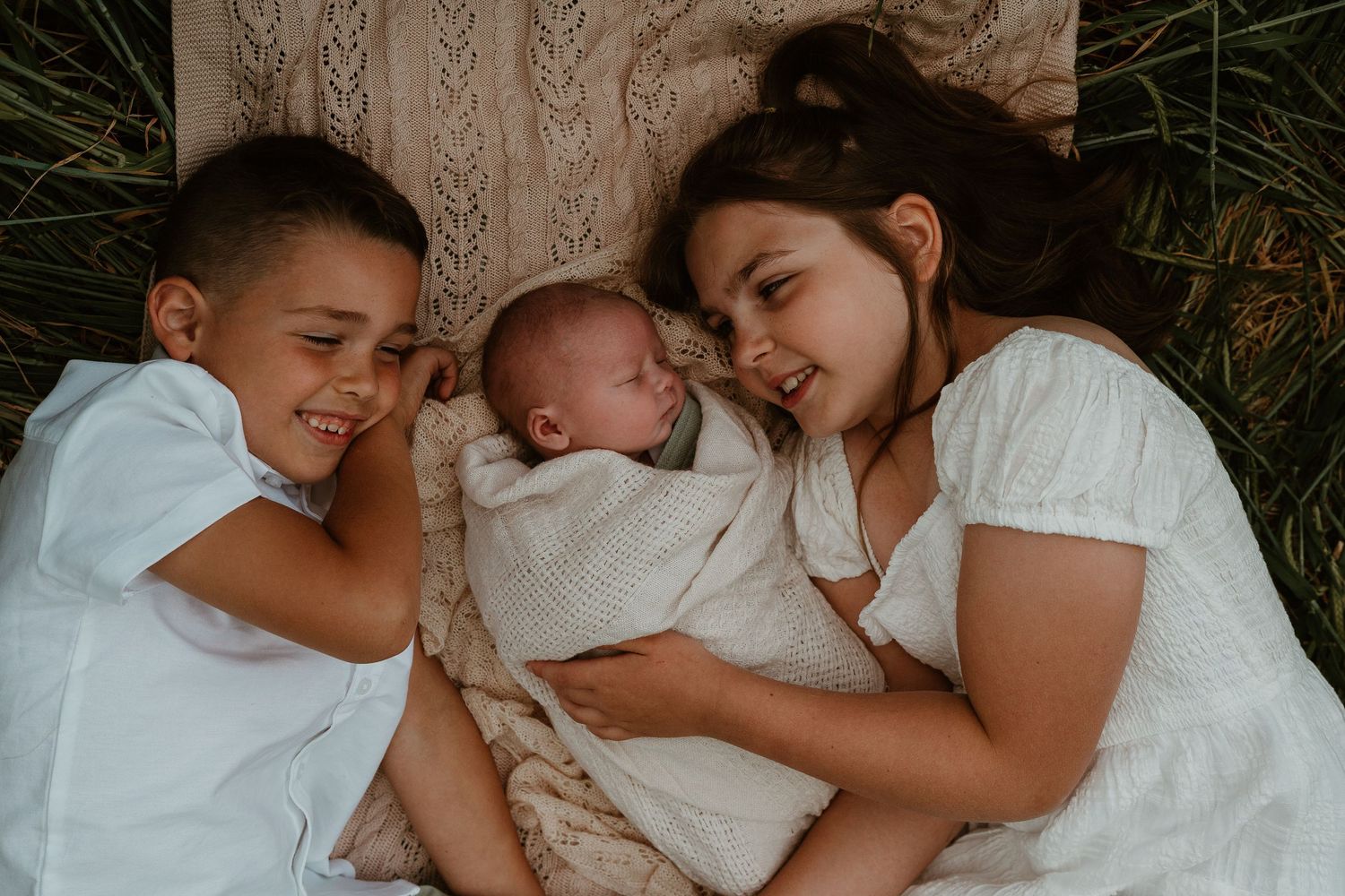 Intimate family moments captured in soft lighting while lying together on grass for photoshoot.