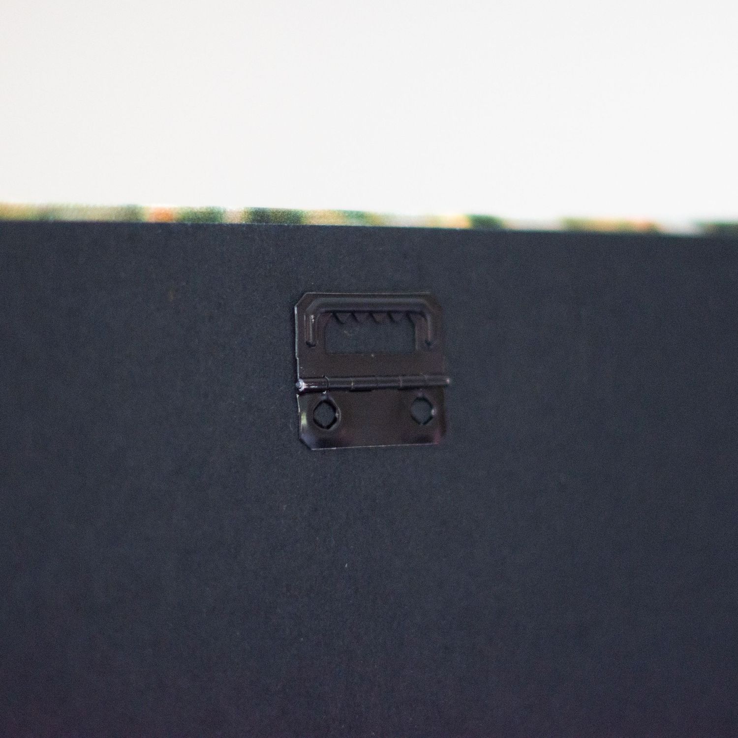 Close-up of black mounting hardware on dark photo album surface.