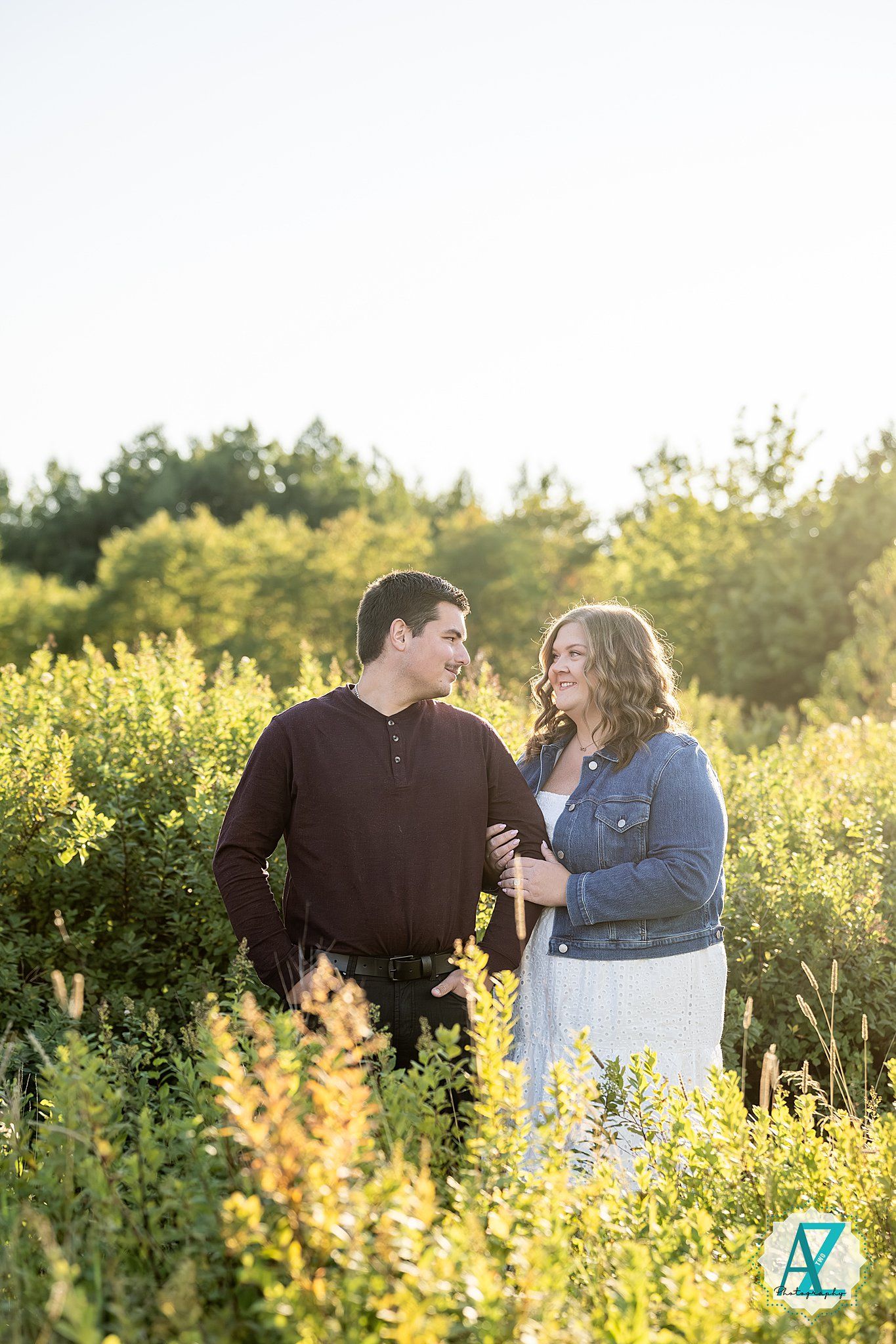 A happy couple sharing a romantic moment surrounded by golden wildflowers in a sunlit meadow during sunset.