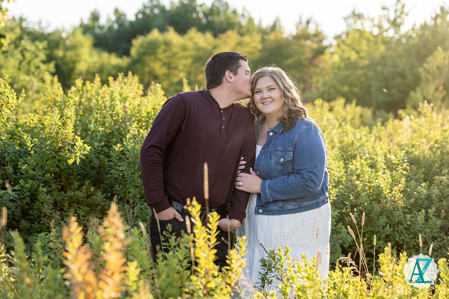 A couple poses together in a golden meadow during sunset with vibrant yellow wildflowers in the background.