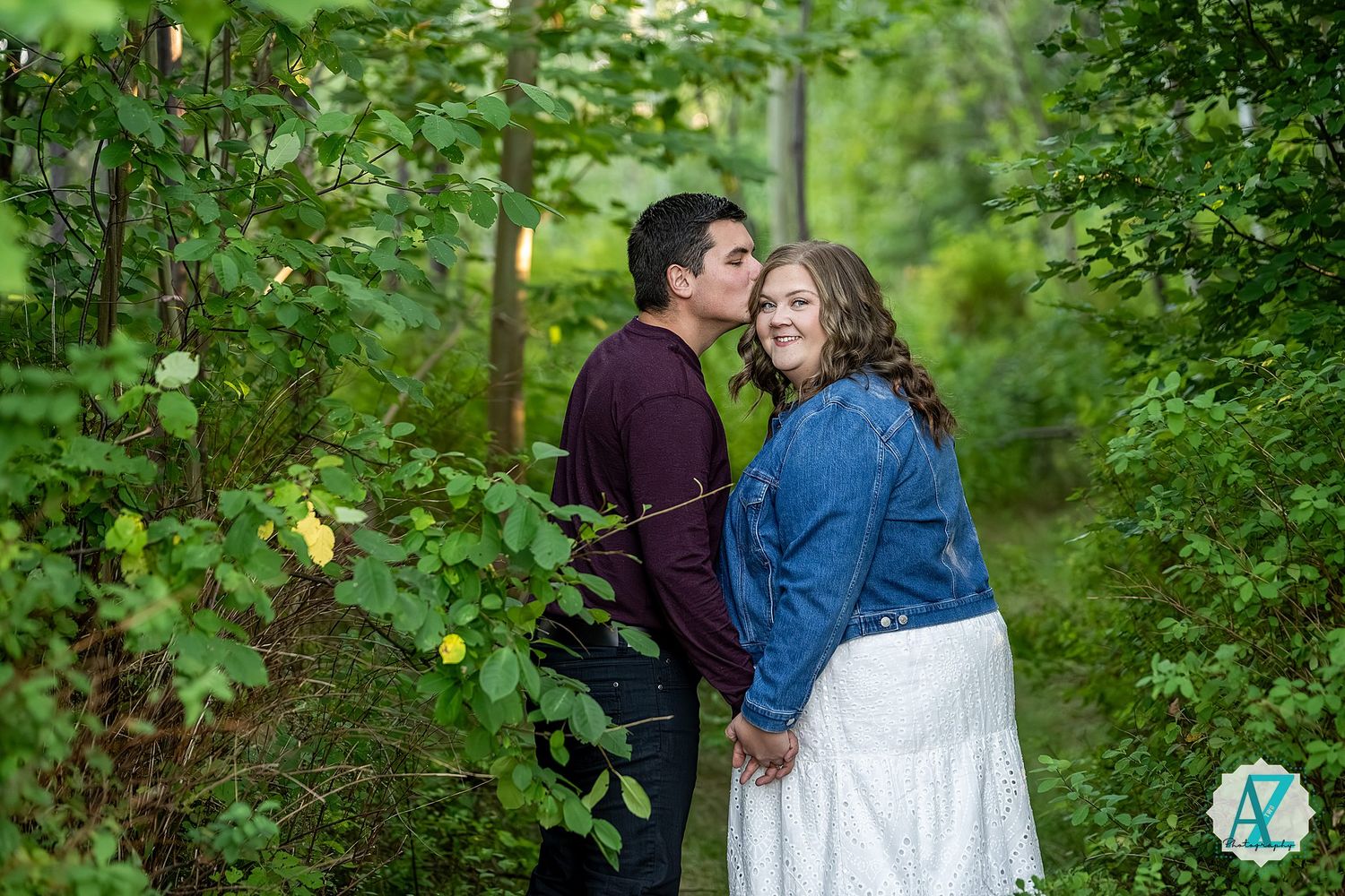 A romantic couple shares a tender moment along a green garden path in summer.