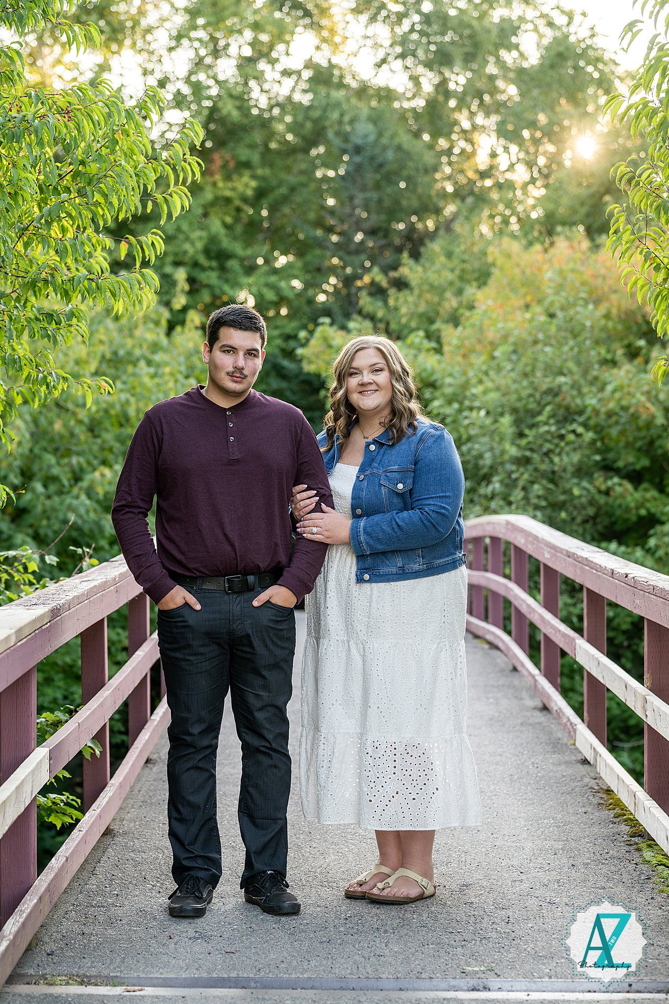 A couple standing on a wooden bridge pathway in a beautiful outdoor natural setting.