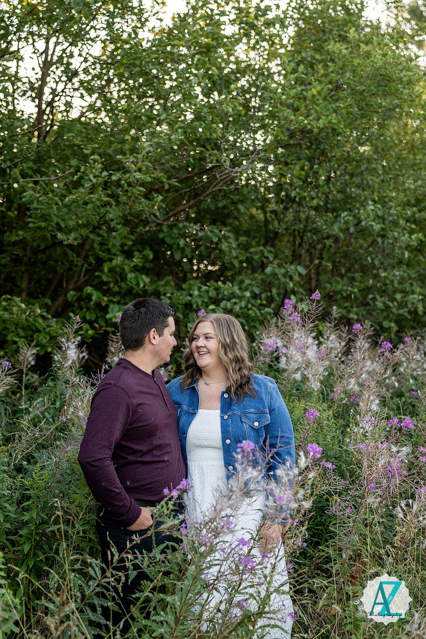 A couple shares a tender moment together in a field of purple wildflowers during sunset.