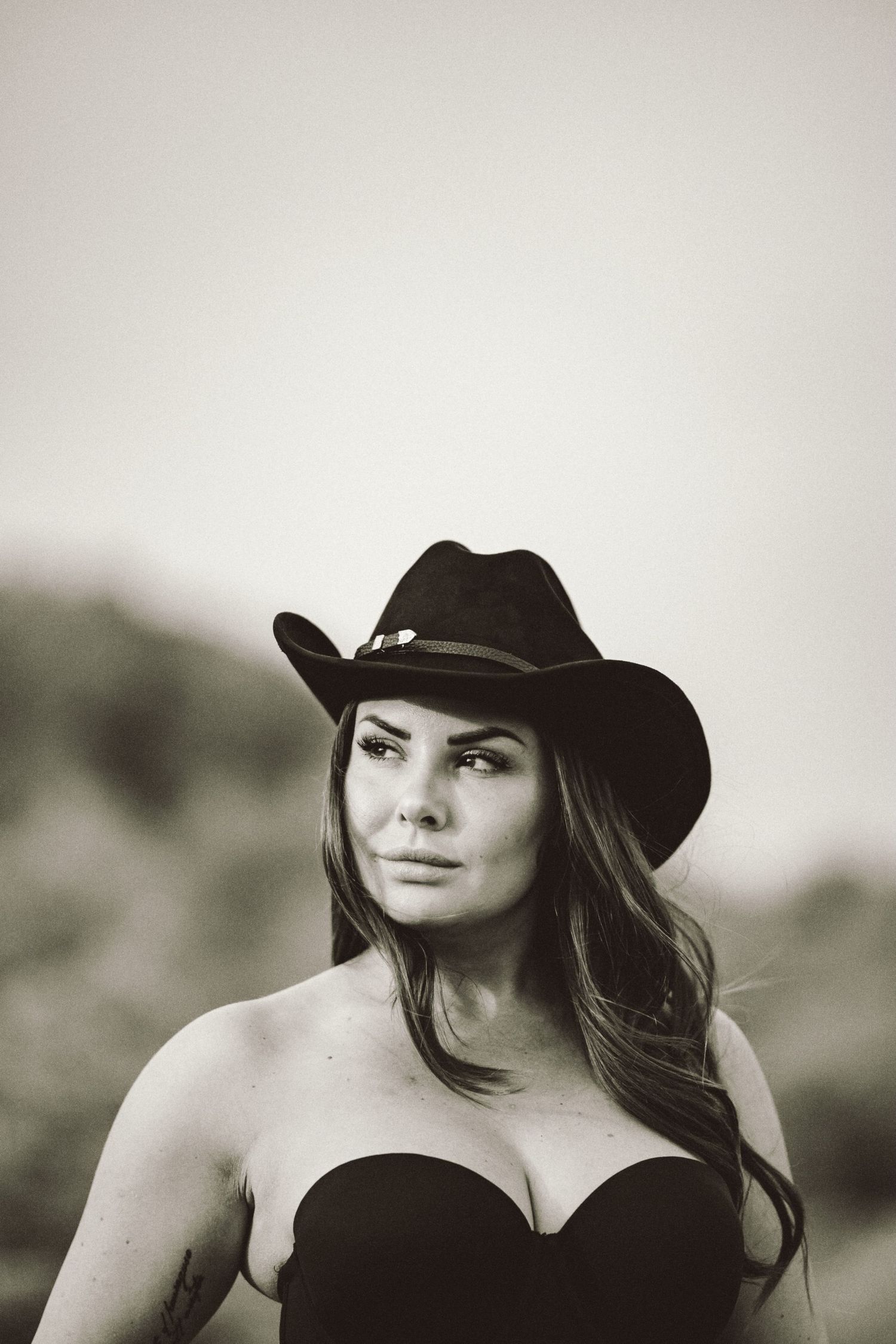 Cowgirl porträtt i svartvitt – kvinna i cowboyhatt och bustier med intensiv blick | Porträttfotograf Malmö