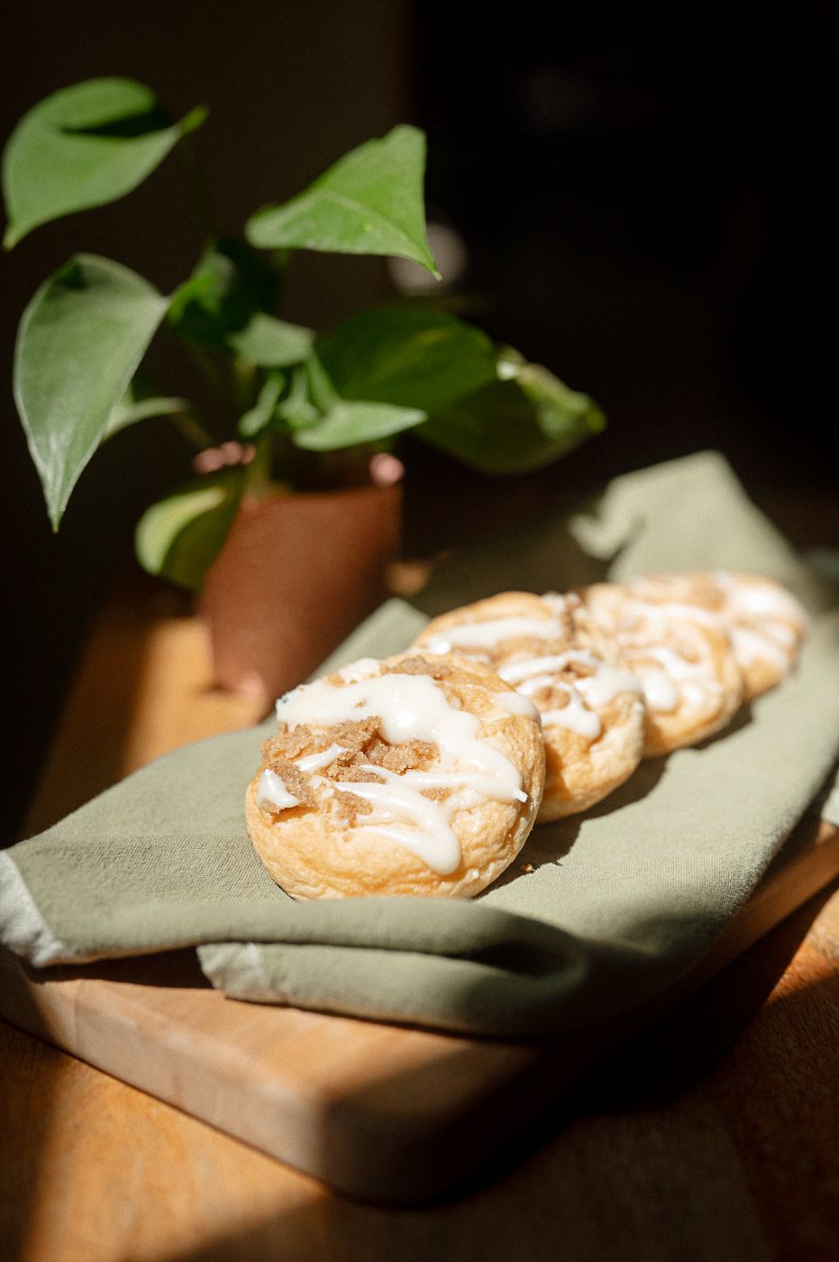 Close-up of golden brown cookies arranged on a gray cloth in dramatic lighting.