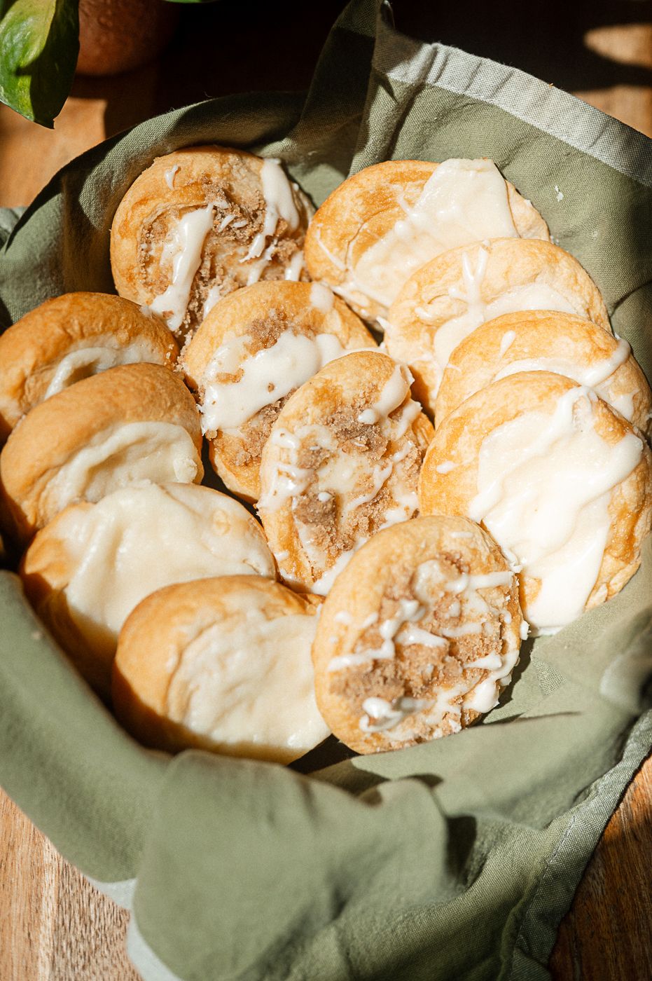 Homemade cream puffs filled with pastry cream and topped with glaze displayed on green parchment paper.