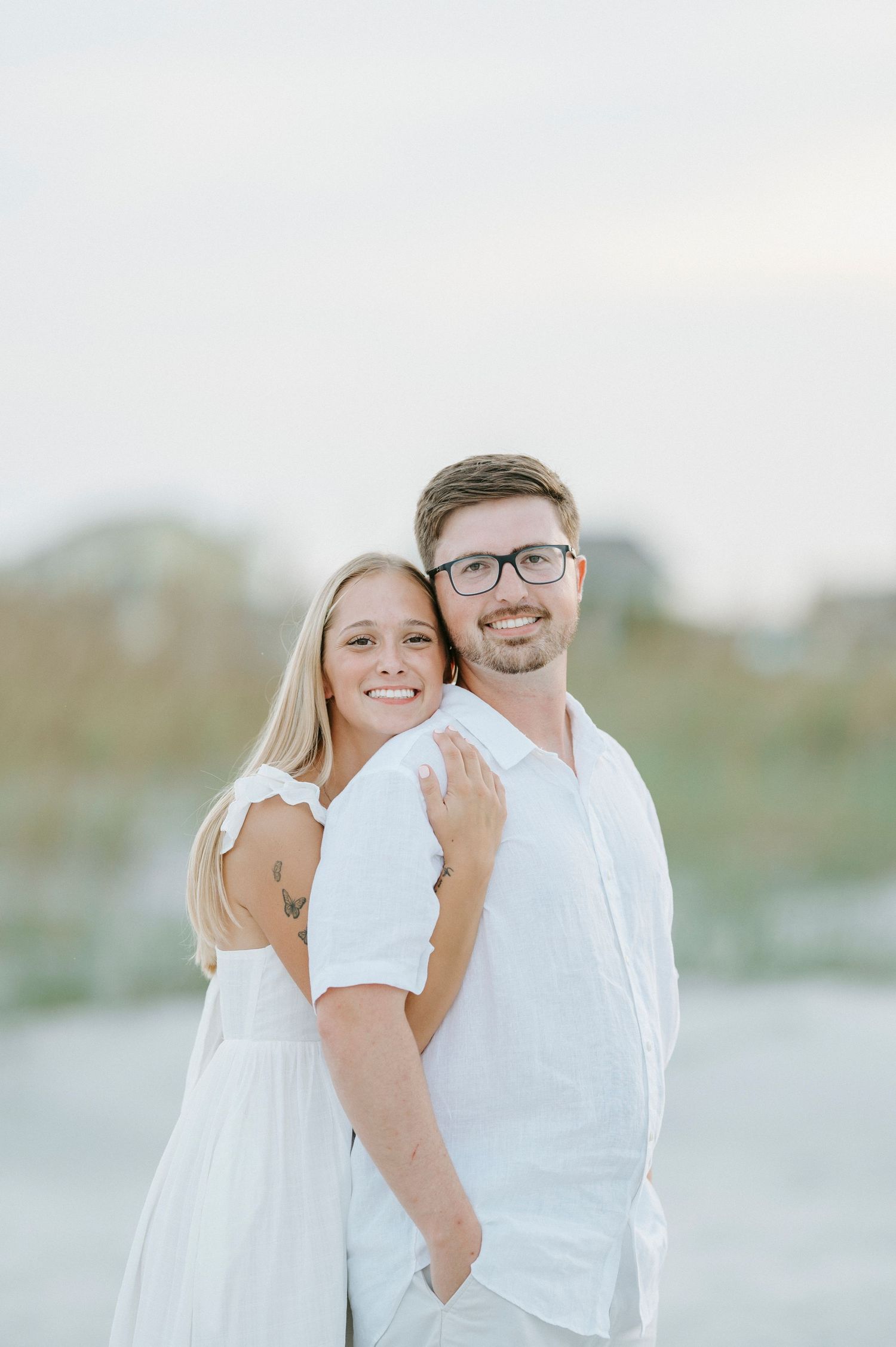 A series of romantic beach portraits showing a couple in white clothing embracing and smiling on a sandy shore.