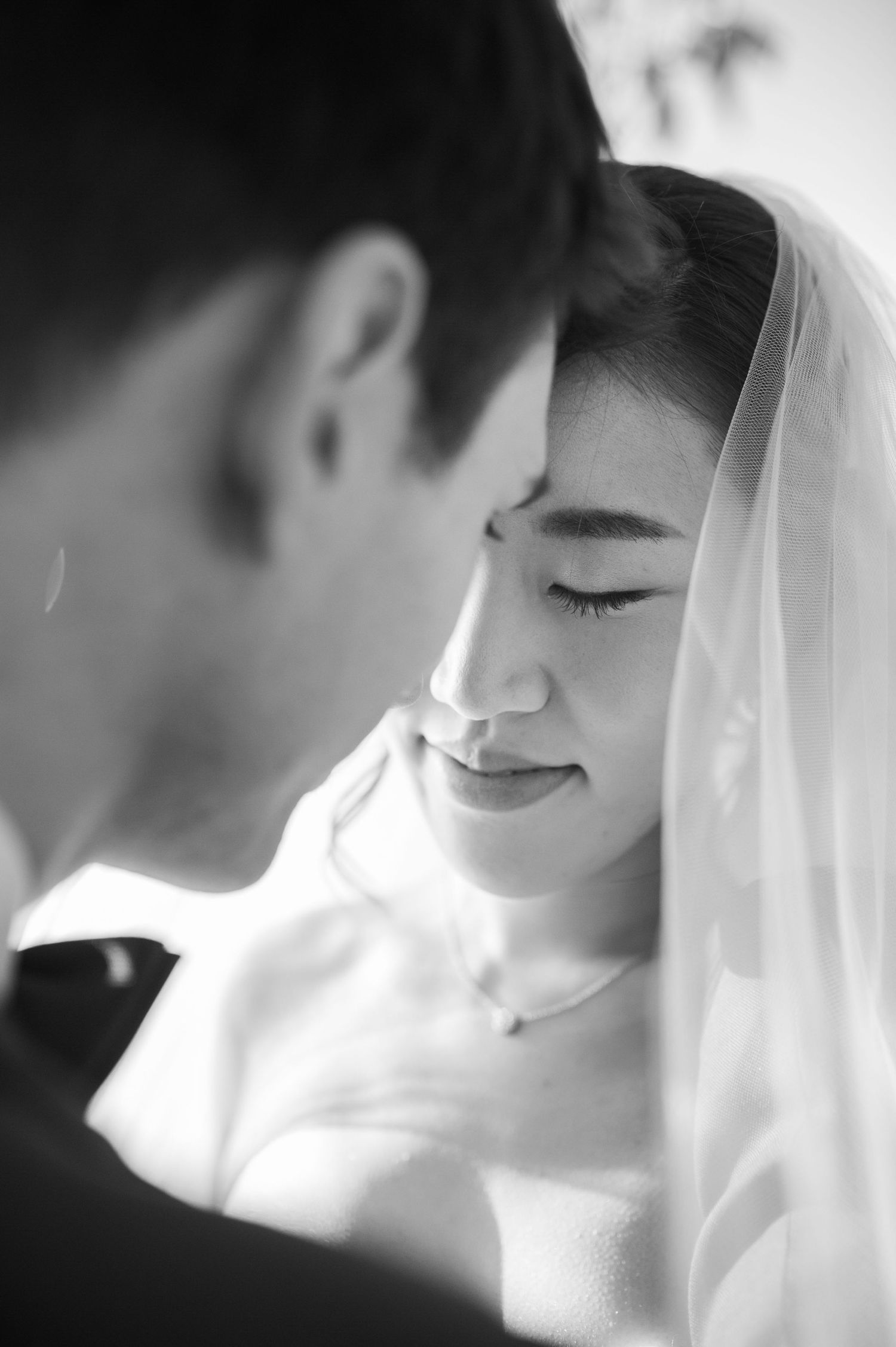Tender black and white wedding photo series showing intimate close-up moments of a couple in soft lighting.