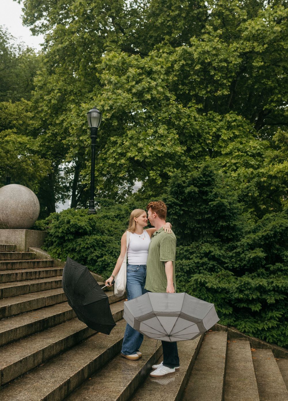 Romantic couple shares tender moments while sitting on curved stone steps surrounded by greenery.