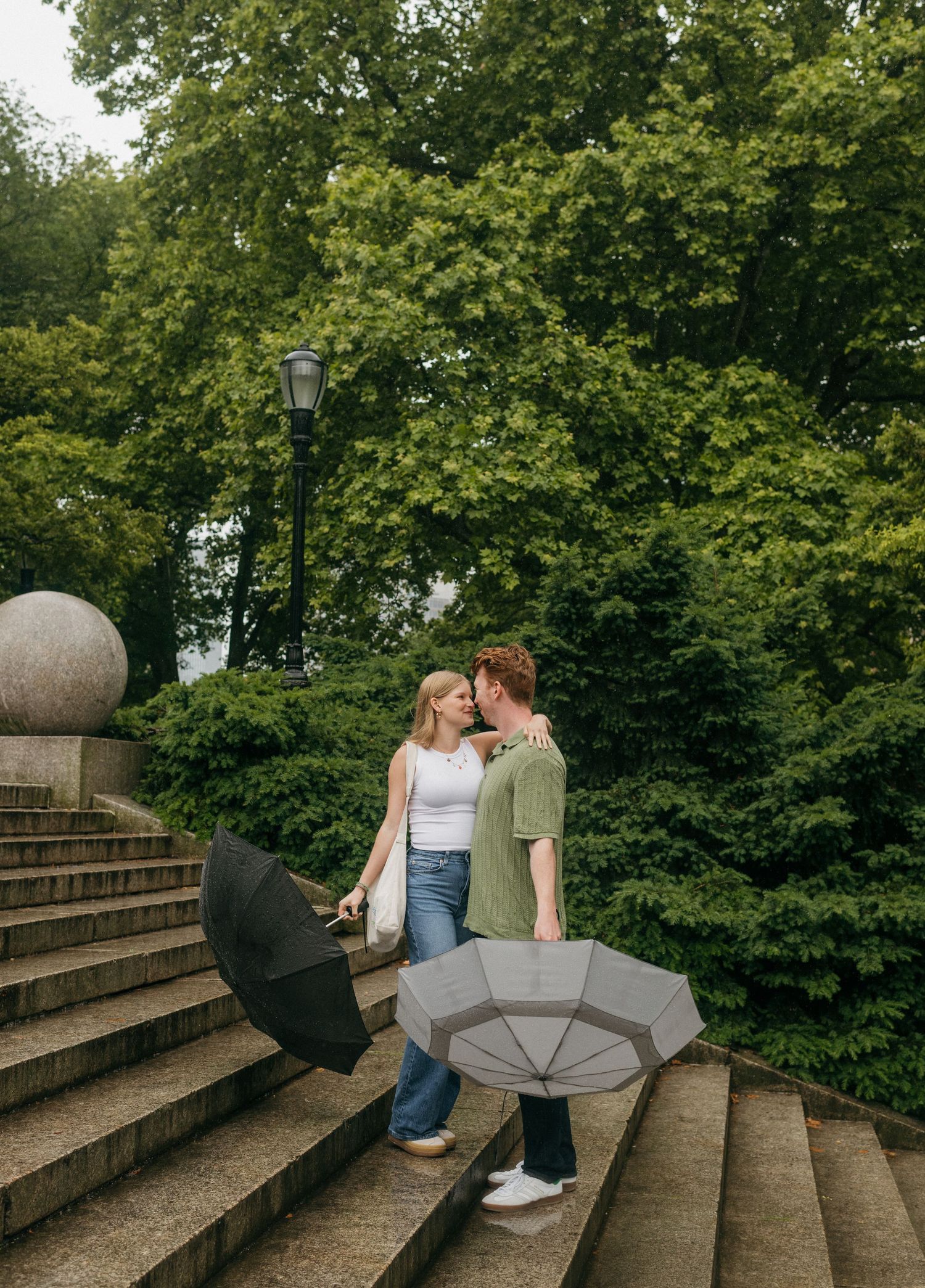 Romantic couple shares tender moments while sitting on curved stone steps surrounded by greenery.