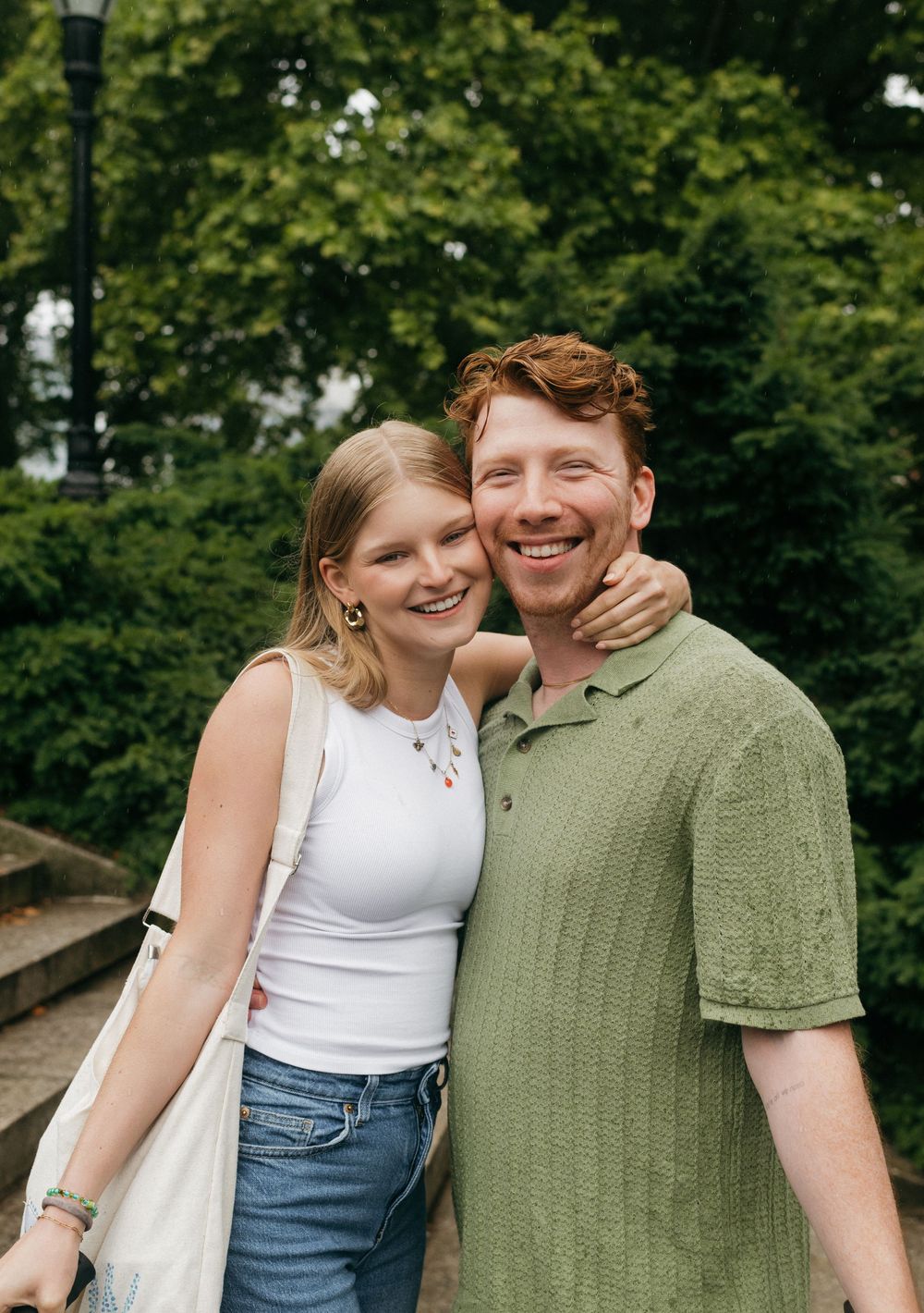 Couple in casual attire sharing joyful moments together in a lush green park setting.
