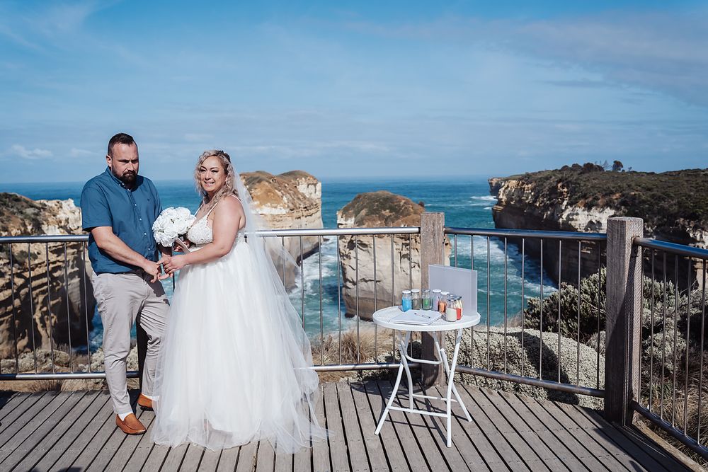 Romantic coastal wedding photoshoot with couples on a scenic wooden boardwalk overlooking the ocean.