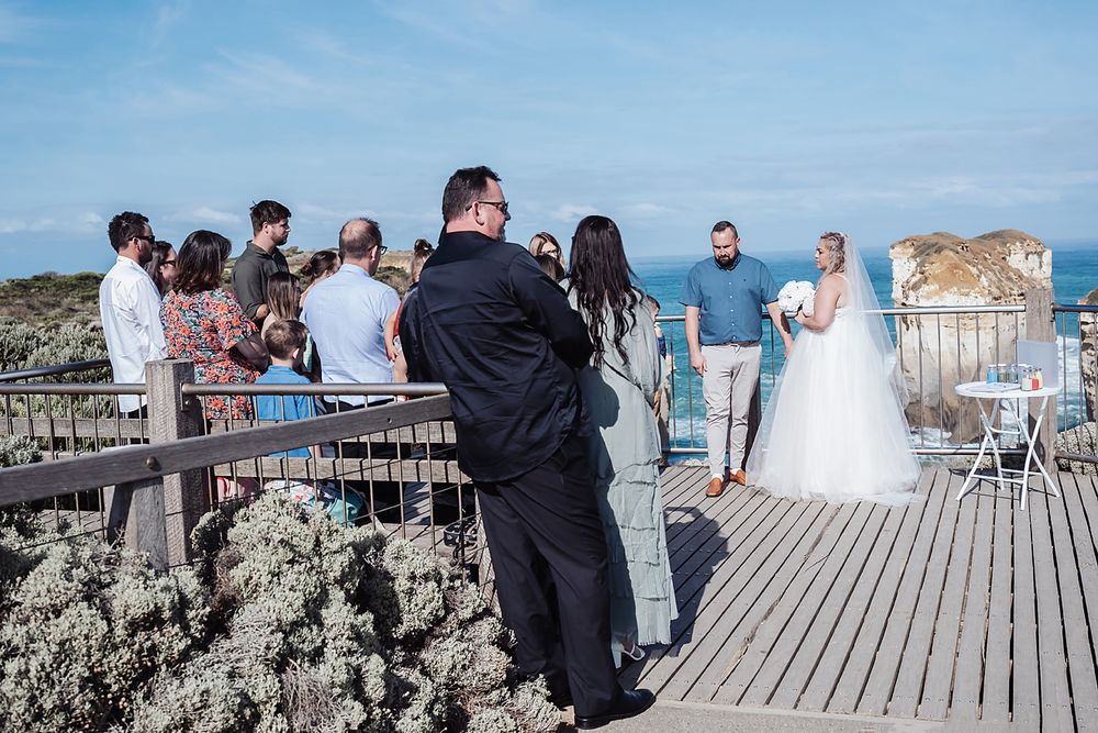 Wedding photoshoot at a scenic coastal boardwalk with blue skies and ocean views in the background.