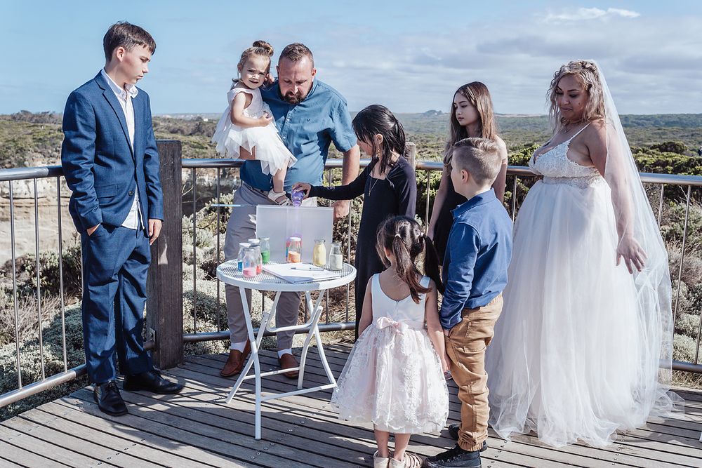 Wedding ceremony participants stand together on a sunny outdoor terrace signing documents and celebrating the occasion.