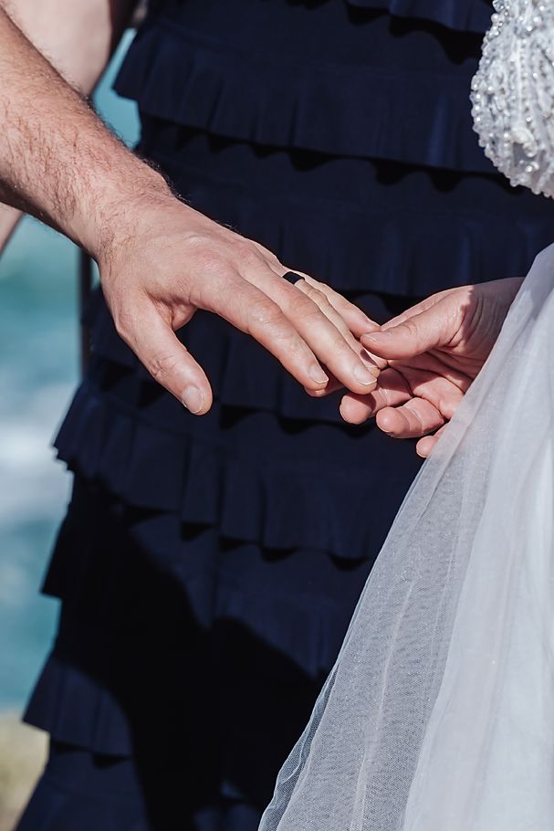 Close up of hands adjusting delicate white tulle fabric details on a wedding dress.