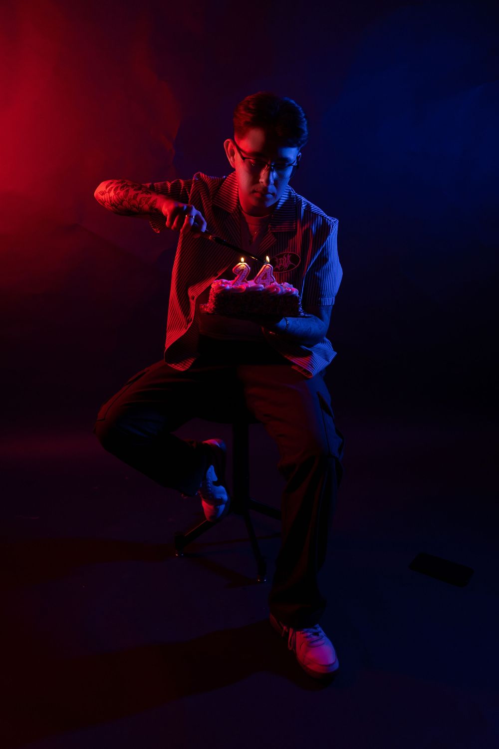 A dancer performs dynamic movements in silhouette against dramatic red and blue lighting on a dark stage.