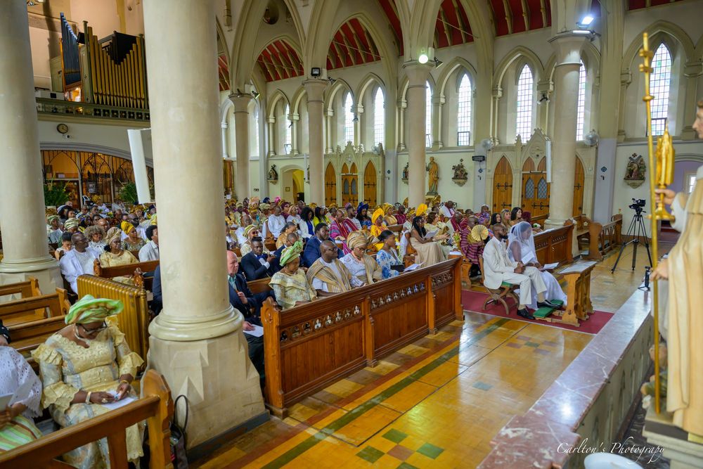 Panoramic view of an elegant church interior with white pillars and wooden pews filled with congregation members during service.