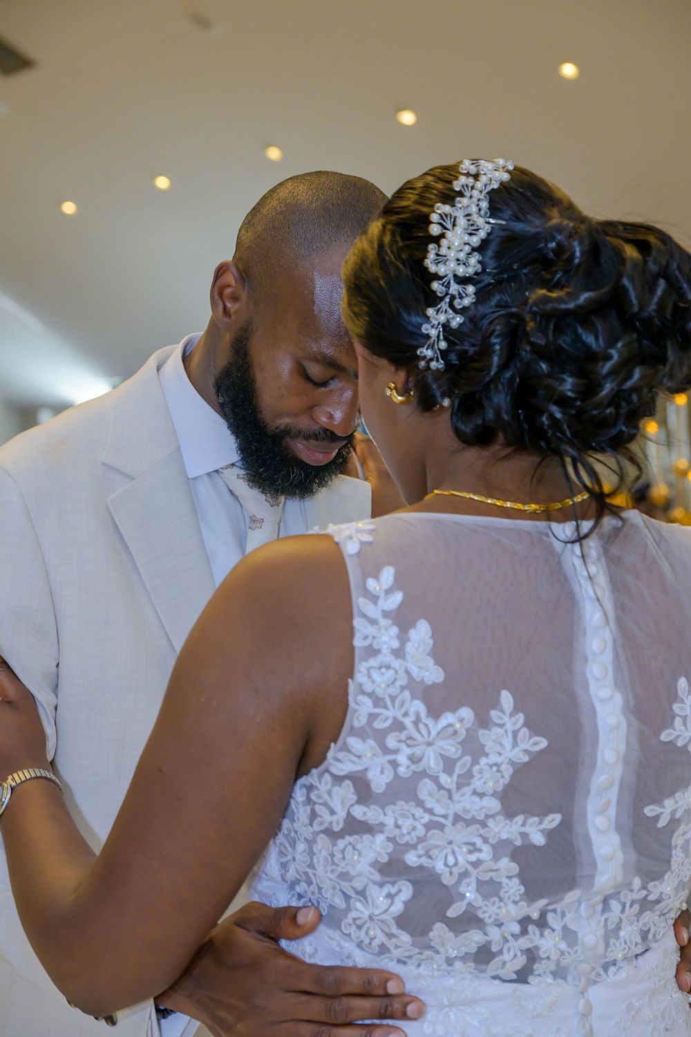 A romantic wedding dance moment captured between a bride in a lace-detailed dress and groom in white suit.