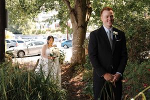 A group of people walk along a garden path lined with trees and bushes.
