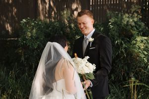 A bride and groom share romantic moments during their outdoor wedding photo session in a lush garden setting.