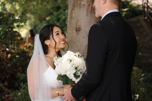 A couple shares a romantic moment during their outdoor wedding ceremony, with the bride holding a white bouquet.